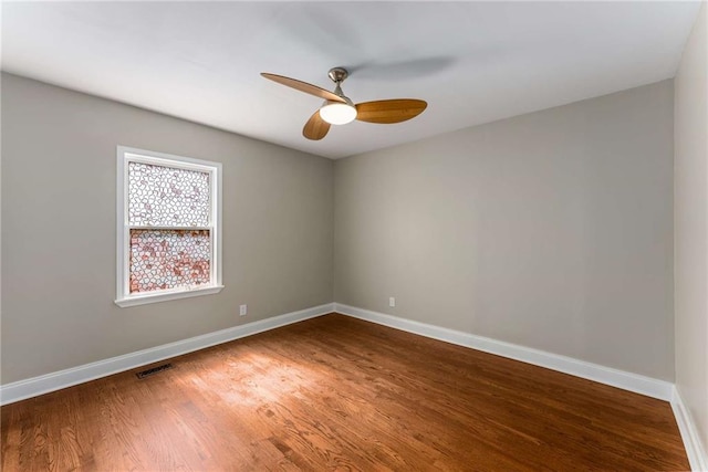 spare room featuring a ceiling fan, baseboards, visible vents, and wood finished floors