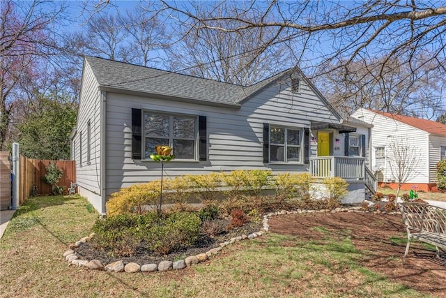 view of front of home with a shingled roof, a front yard, and fence