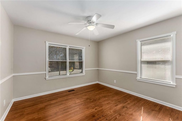 spare room featuring baseboards, visible vents, and wood finished floors