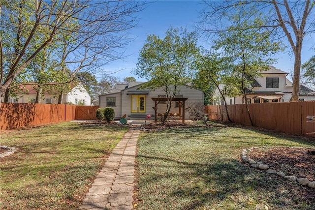 rear view of house with a fenced backyard and a yard