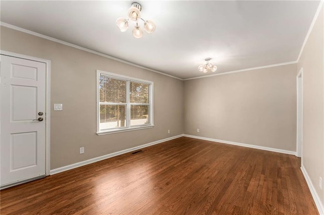 spare room featuring baseboards, visible vents, ornamental molding, wood finished floors, and a notable chandelier