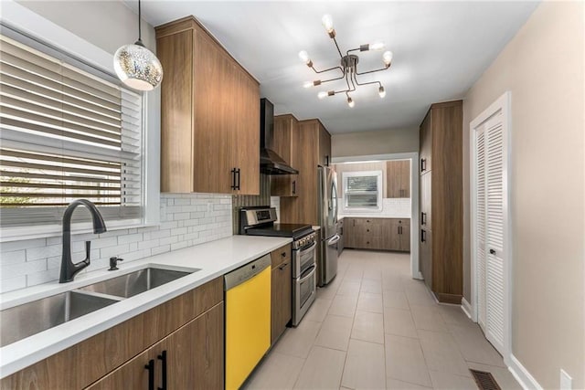 kitchen with stainless steel appliances, visible vents, backsplash, a sink, and wall chimney range hood