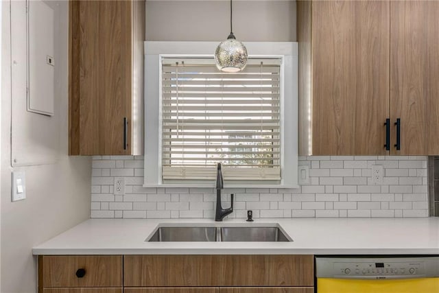 kitchen featuring tasteful backsplash, light countertops, dishwasher, and a sink