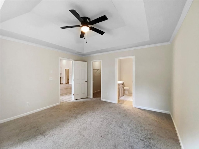 1792 Portwest Way, Hampton, GA 30228 - unfurnished bedroom featuring a tray ceiling, a walk in closet, light carpet, crown molding, and baseboards