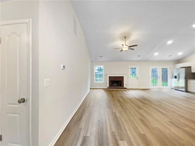 1792 Portwest Way, Hampton, GA 30228 - unfurnished living room with a ceiling fan, a brick fireplace, plenty of natural light, vaulted ceiling, and light wood-type flooring
