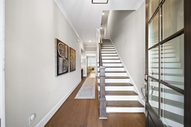 stairway with ornamental molding and wood-type flooring