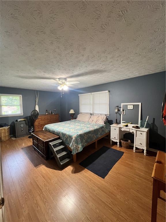 2194 Meadow Dr, Snellville, GA 30078 - bedroom featuring wood finished floors, a textured ceiling, and a ceiling fan