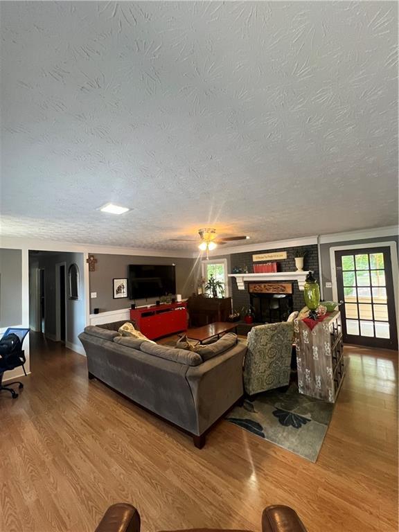 2194 Meadow Dr, Snellville, GA 30078 - living area with wood finished floors, a textured ceiling, plenty of natural light, a fireplace, and baseboards