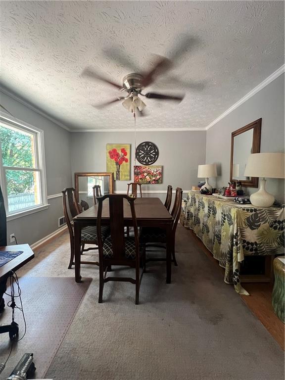 2194 Meadow Dr, Snellville, GA 30078 - dining space featuring ceiling fan, ornamental molding, a textured ceiling, and dark carpet