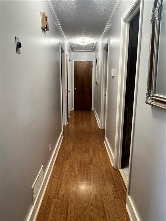 2194 Meadow Dr, Snellville, GA 30078 - corridor featuring attic access, wood finished floors, a textured ceiling, baseboards, and crown molding