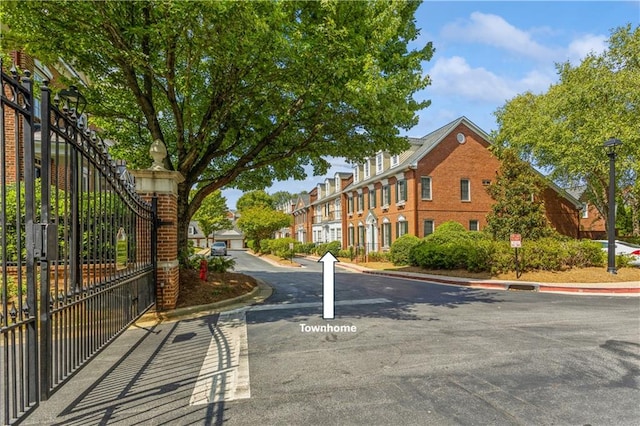 view of street featuring a gate, street lights, and curbs