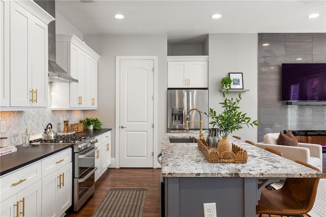 1202 Hardee St NE, Atlanta, GA 30307 - kitchen featuring stainless steel appliances, a kitchen island with sink, dark wood finished floors, a breakfast bar, and wall chimney range hood
