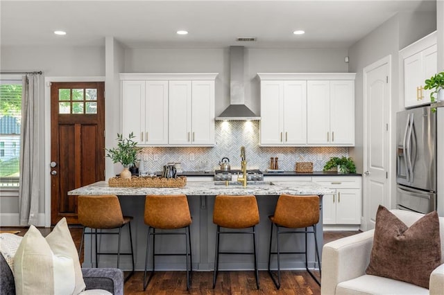 1202 Hardee St NE, Atlanta, GA 30307 - kitchen featuring wall chimney range hood, stainless steel fridge with ice dispenser, white cabinets, an island with sink, and backsplash