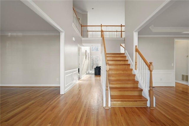 stairway with hardwood / wood-style floors and crown molding