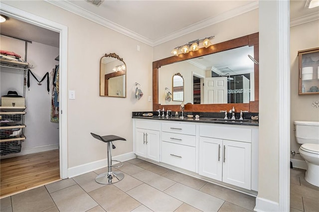 full bath featuring toilet, crown molding, tile patterned floors, double vanity, and baseboards