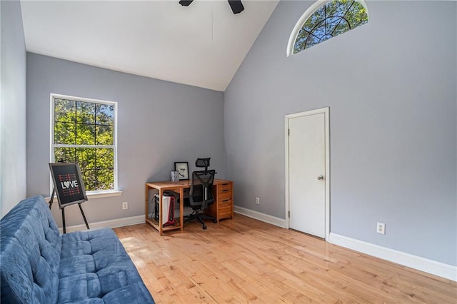 office space featuring high vaulted ceiling, healthy amount of natural light, light wood-style flooring, ceiling fan, and baseboards