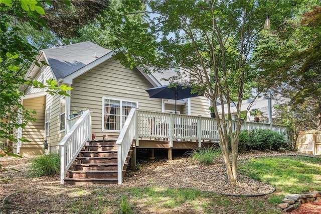 rear view of house with a wooden deck, fence, and stairs