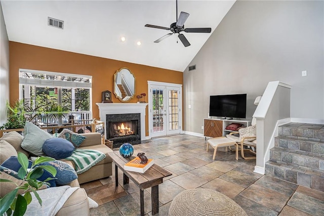 living area with high vaulted ceiling, plenty of natural light, baseboards, a ceiling fan, and a fireplace