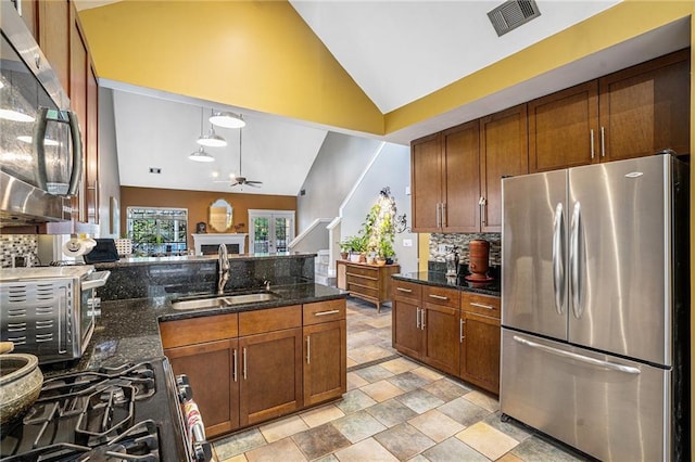 kitchen with appliances with stainless steel finishes, a sink, a ceiling fan, decorative backsplash, and light stone finish floors