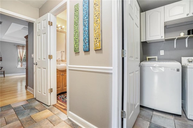 laundry area with baseboards, washer and clothes dryer, light stone finish floors, and cabinet space
