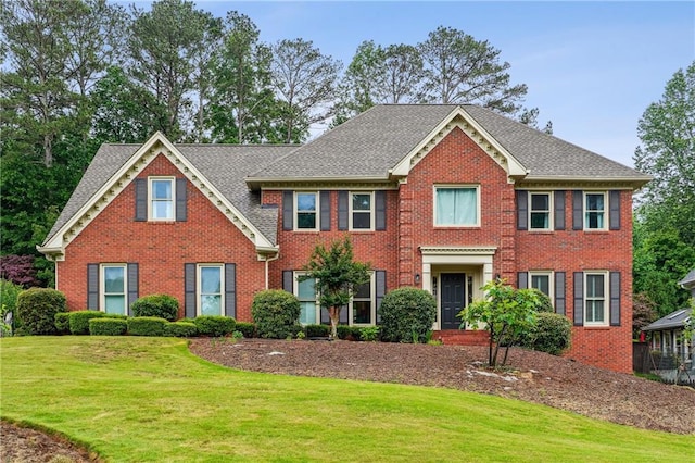 colonial house featuring brick siding, a front lawn, and roof with shingles