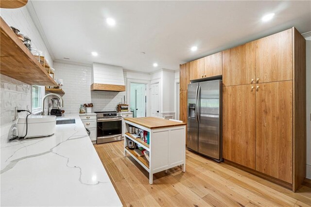 kitchen with open shelves, appliances with stainless steel finishes, custom range hood, a sink, and wooden counters