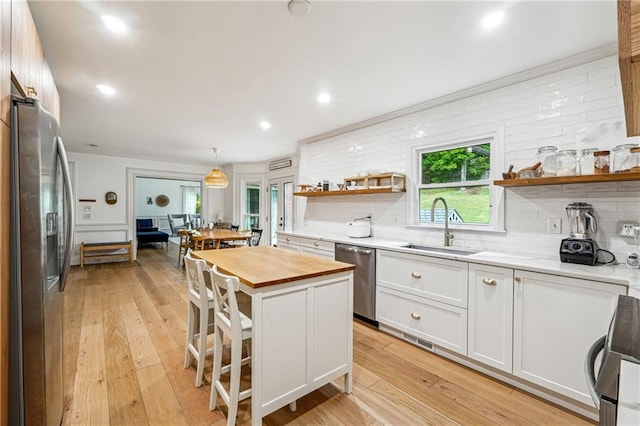 kitchen with stainless steel appliances, open shelves, wood counters, a sink, and light wood-style flooring