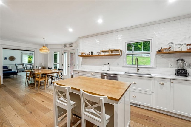 kitchen with a sink, open shelves, dishwasher, white cabinets, and light wood-type flooring