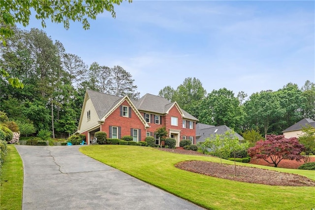 view of front of home featuring brick siding, a front lawn, a garage, and asphalt driveway