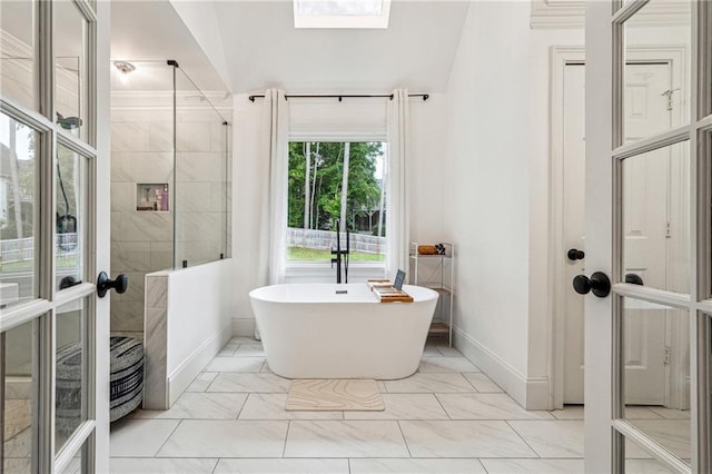 full bathroom with marble look tile flooring, a freestanding tub, baseboards, vaulted ceiling, and tiled shower