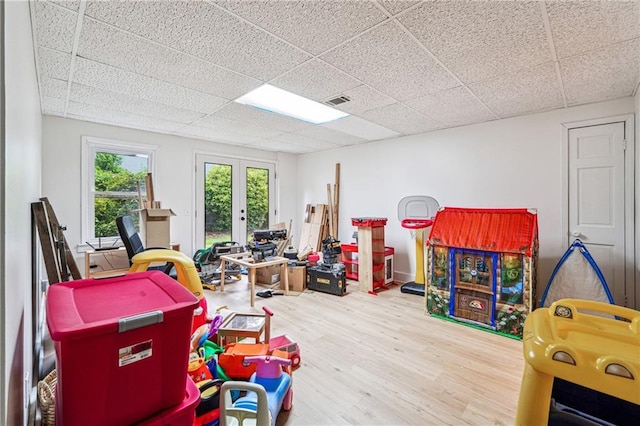 recreation room featuring french doors, wood finished floors, and a paneled ceiling