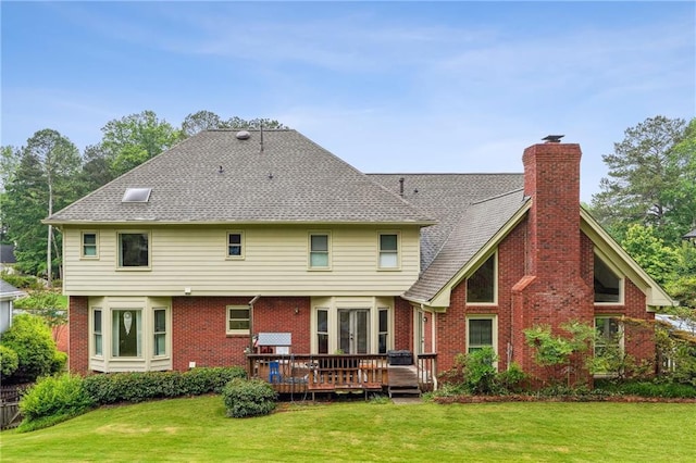 rear view of house with a wooden deck, a yard, brick siding, and a chimney
