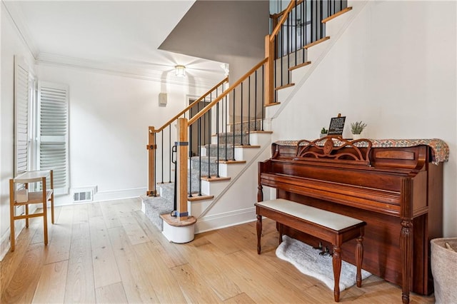 stairway with ornamental molding, wood finished floors, and baseboards