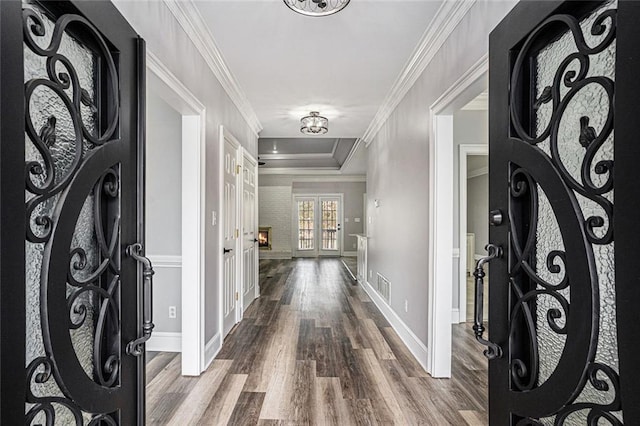 foyer entrance with french doors, ornamental molding, a tray ceiling, and wood-type flooring