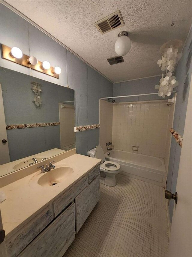 full bathroom featuring tile patterned floors, toilet, a textured ceiling, vanity, and tiled shower / bath combo