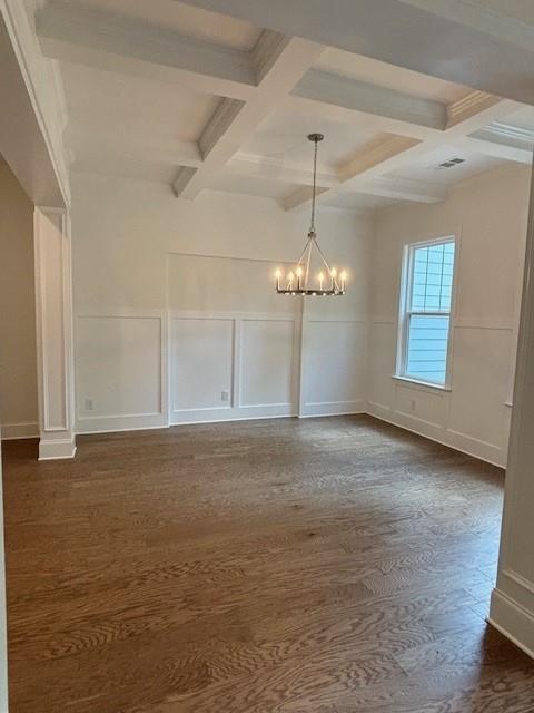 unfurnished room with beam ceiling, a chandelier, dark wood-type flooring, and coffered ceiling