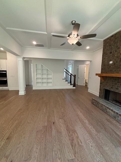 unfurnished living room featuring hardwood / wood-style flooring, built in shelves, ceiling fan, and a brick fireplace