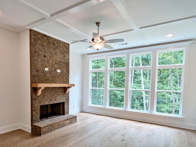 unfurnished living room with hardwood / wood-style flooring, ceiling fan, coffered ceiling, and a brick fireplace