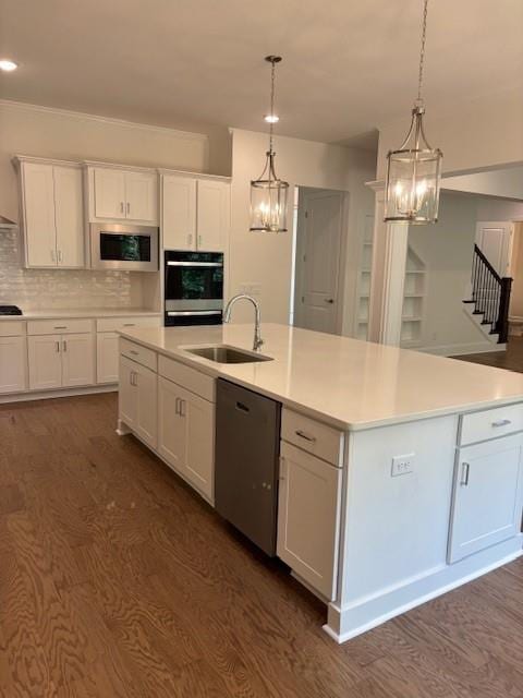 kitchen featuring stainless steel dishwasher, a center island with sink, and white cabinetry