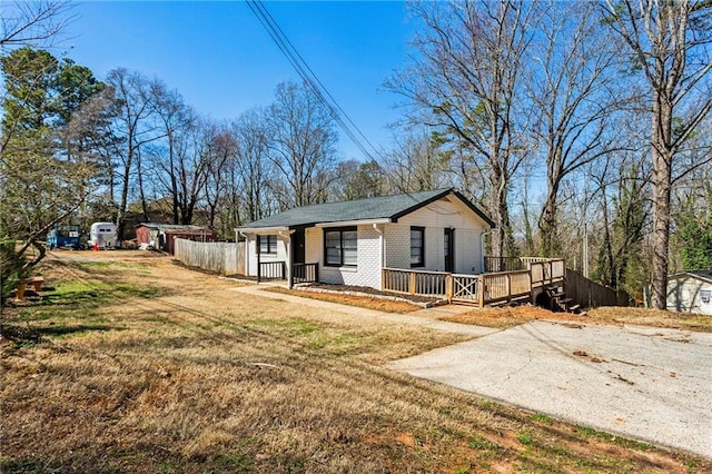 view of front of property featuring driveway, brick siding, a front lawn, and fence