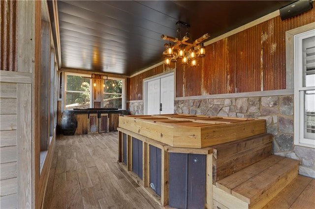 interior space with hanging light fixtures, wood walls, wood-type flooring, and a notable chandelier