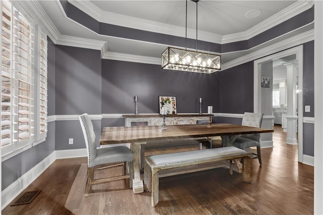 dining area featuring ornamental molding, dark wood-type flooring, and a chandelier