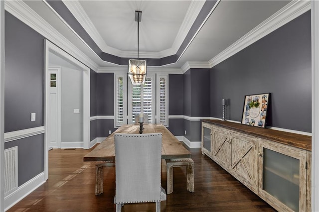 dining room featuring a tray ceiling, dark hardwood / wood-style floors, a chandelier, and crown molding