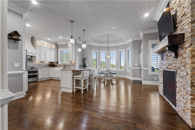 kitchen with white cabinetry, plenty of natural light, stainless steel stove, and a breakfast bar