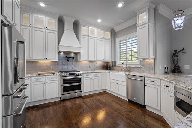 kitchen with white cabinetry, stainless steel appliances, decorative light fixtures, and premium range hood