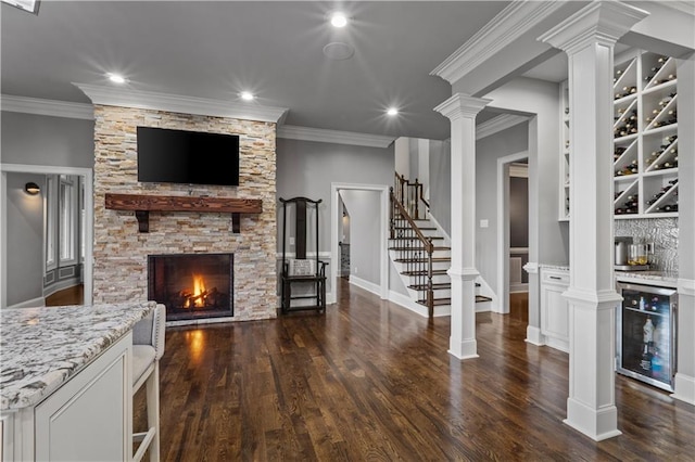 living room with a fireplace, crown molding, dark hardwood / wood-style flooring, ornate columns, and wine cooler