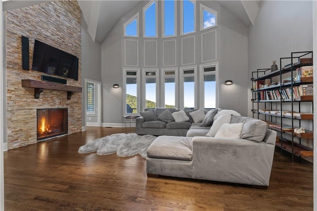 living room with hardwood / wood-style floors, a stone fireplace, and high vaulted ceiling