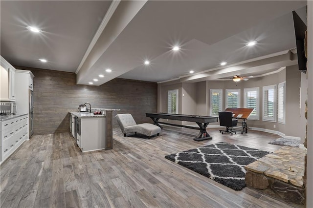 interior space with billiards, hardwood / wood-style floors, wooden walls, appliances with stainless steel finishes, and a center island with sink