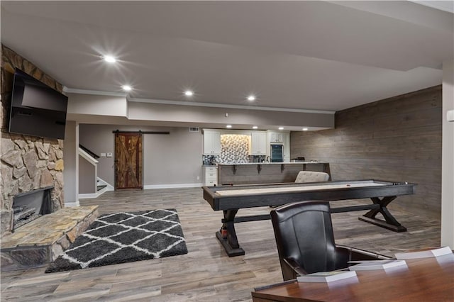 rec room featuring a barn door, a fireplace, and light hardwood / wood-style flooring