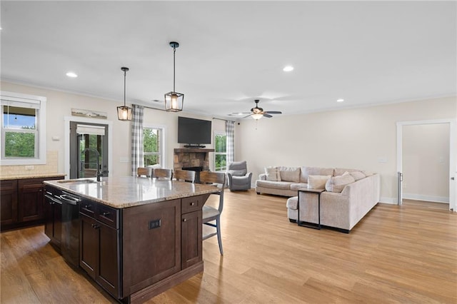 415 Stoneledge Rd, Jasper, GA 30143 - kitchen featuring a breakfast bar area, a fireplace, dark brown cabinetry, light wood-type flooring, and light stone countertops